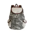Detailed view of canvas zebra print backpack with brown leather trim and front pocket details. - Black and White Zebra Print (sj2691)