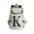 Close-up detail of canvas backpack with floral letter print, brown leather trim, and snap flap. - Letter K Print Style (sj2468)