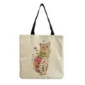 Close-up detail of the floral cat print and sturdy black strap on the canvas tote bag. - Light Linen Floral Cat Print (hm9294)