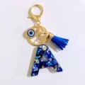 Blue letter A keychain with evil eye charm and blue tassel, resin gold tone accessory. - Letter A