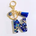 Blue letter N resin keychain with evil eye charm and tassel, stylish bag accessory detail. - Letter N
