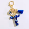 Blue initial T letter keychain with gold chain, leather tassel and evil eye charm detail. - Letter T