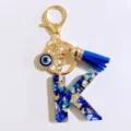Blue letter K resin keychain with gold tone hardware, evil eye charm and blue tassel. - Letter K