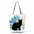Detail view of the black cat and blue hydrangea watercolor print on the canvas tote bag. - Black Cat and Blue Hydrangea (hlk2484)