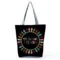 Close-up detail of the black canvas tote bag featuring a colorful teacher themed print design. - Style Thirteen (hl5401)