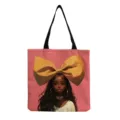 Détail du sac cabas en toile avec un portrait féminin élégant et un grand nœud jaune. - Style de Grand Nœud Fond Rose (hmk3507)