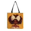 Vue détaillée du sac en toile avec impression graphique d'une élégante femme noire et ruban. - Style de Fond Jaune Vif Avec Croix (hmk3510)