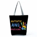 Close-up detail of a black canvas tote bag featuring colorful handprint graphic and text. - Style Eighteen (hl5406)