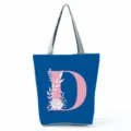 Blue tote bag detail view, featuring large pink letter D print and floral design, stylish. - Letter D