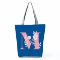 Blue tote bag with pink letter M and floral print, stylish and spacious shoulder handbag. - Letter M