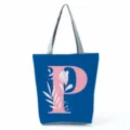 Detailed view of blue tote bag with pink letter P and floral print, zipper and grey handles. - Letter P