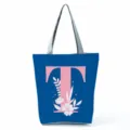 Detailed view of the blue canvas tote bag featuring a pink letter T and floral print design. - Letter T