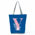 Close-up detail of the blue canvas tote bag featuring a pink letter Y and white floral print. - Letter Y