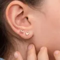 Primo piano dettagliato di delicati orecchini a lobo con lettera M e cuore in oro rosa. - Stile Iniziale A (A) / Oro rosa