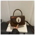 Chic brown patent leather shoulder bag with stylish round metal clasp for women daily commute. - Brown