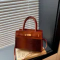 Stylish brown shoulder handbag with crocodile texture, top handle and lock closure design. - Brown