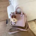 Vue détaillée du sac à main élégant en cuir rose avec un joli pendentif chiot en peluche. - Pendentif chiot avec nœud