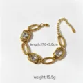 Primo piano dettagliato del bracciale in acciaio dorato con cristalli quadrati e maglie. - Bianco