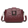 Sac bandoulière en cuir bordeaux avec lettres gaufrées et boucle carrée élégante. - Rouge