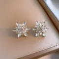 Close-up of sparkling crystal flower stud earrings on a gold satin tray, elegant detail shot. - Rhinestone Flower Style (32#) / Silver Post Alloy Version / White