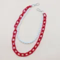 Detailed shot of trendy red acrylic and faux pearl chain strap for bags or pants accessories. - Red