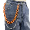 Close-up detail of double-layer hip-hop pants chain with bright orange acrylic and silver metal. - Orange