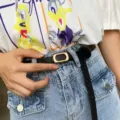 Minimalist black thin leather belt detail, featuring a sleek gold rectangular metal buckle. - Black