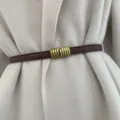 Detailed view of a chic brown thin leather belt with a vintage gold metal buckle worn on coat. - Coffee