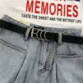 Women punk style black leather belt with metal rings and chain paired with denim jeans. - Black