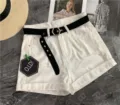 White denim shorts for women featuring black canvas belt and hexagonal buckle. Casual summer wear. - 105cm / Black