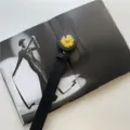 Detail view of stylish black leather belt featuring a cute yellow daisy flower buckle. - Daisy Black Style D