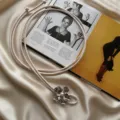 Detailed shot of a chic beige soft leather rope belt featuring a metallic flower and pearl pendant. - Off White