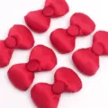 Détail de nœuds en tissu satiné rembourré rouge montrant une texture lisse et un bouton pour bricolage. - Personnaliser D'autres Styles Style