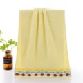 Yellow cotton face towel with embossed circles and colorful striped border design for home. - Interlocking Rings Style, Yellow