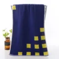 Detailed view of dark blue cotton face towel featuring stylish yellow square geometric patterns. - Yellow Cube