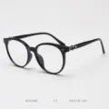 Close-up detail of black round eyeglass frame featuring ornate silver temple decorations. - Glossy Black C1