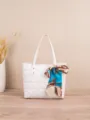 Detailed view of white quilted tote bag featuring elegant blue printed silk scarf accessory. - White