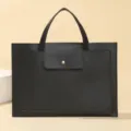 Close up view of the black leather laptop handbag showcasing its sleek design and front pocket. - Black