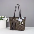 Nahaufnahme der dunkelbraunen Monogramm-Tragetasche mit Münzbeutel und elegantem Seidenschal. - Kaffeebraun