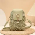 Detailaufnahme einer salbeigruenen Mini Handytasche mit Stoffrosen und Perlenanhaenger. - Grün