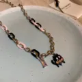 Close-up detail of the black anime creature pendant necklace with pink crystals and mixed chain. - Black Pink Patchwork Cat (3#)