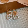 Nahaufnahme der stilvollen geometrischen Kettenohrringe mit eleganten weiß-goldenen Strukturgliedern. - Weißer Kettenstil (1#) / Weiß