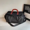 Large capacity travel duffle bag with grid front pocket and red handles for sports gym trips. - Black