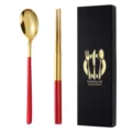 Set di posate in acciaio inossidabile con cucchiaio oro e bacchette rosse in scatola nera. - Set cucchiaio e bacchette in rosso e oro