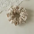 Gros plan d'un chouchou à cheveux vintage à motif écossais beige et marron texture douce. - S / Carreaux Kaki