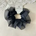 Detailaufnahme eines eleganten schwarzen Organza und Satin Haargummis für stilvolles Haar. - Satin Organza Doppelschicht Nähte / Schwarz