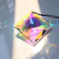 Detailed shot of large crystal suncatcher prism pendant, throwing vibrant rainbow lights. - 55mm Square Bead