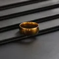 Gros plan de détail d'une bague anneau unie dorée minimaliste sur fond sombre texturé. - Anneau Lisse Simple (01093) / Or