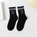 Black cotton mid-calf socks with white double stripes and cute knit smiley face pattern. - One Size / Black