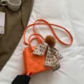 Oranger Mini Umhängetasche mit Karo-Band und Bommel-Anhänger, elegante PU-Ledertasche. - Orange